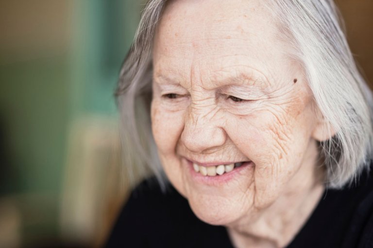 Portrettfoto av eldre kvinne som smiler.